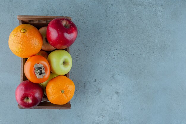 Várias frutas em uma caixa, no fundo de mármore. Foto de alta qualidade