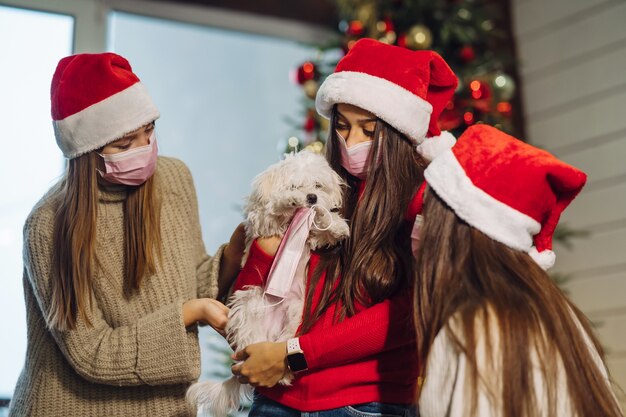 Várias meninas brincam com um cachorrinho na véspera de Ano Novo em casa