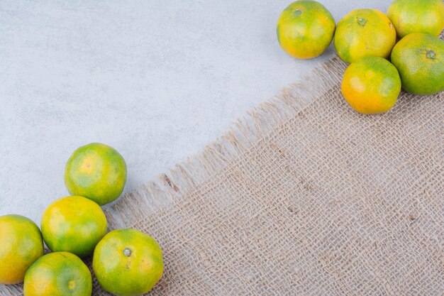 Várias tangerinas frescas e azedas inteiras em pano de saco