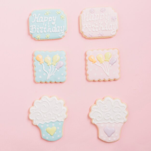 Variedade de biscoitos de confeiteiro de gengibre dispostos em fundo rosa