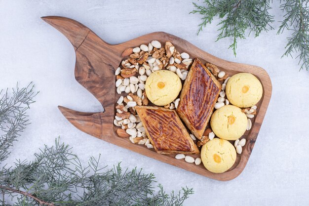 Variedade de biscoitos saborosos em uma placa de madeira com nozes