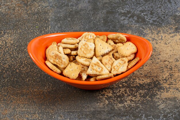 Variedade de biscoitos salgados em uma tigela de laranja.