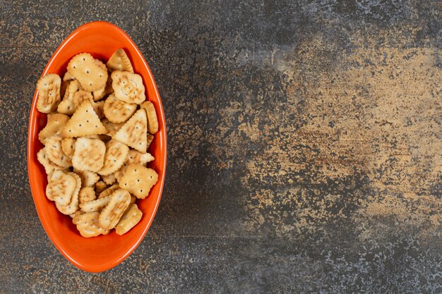 Variedade de biscoitos salgados em uma tigela de laranja.