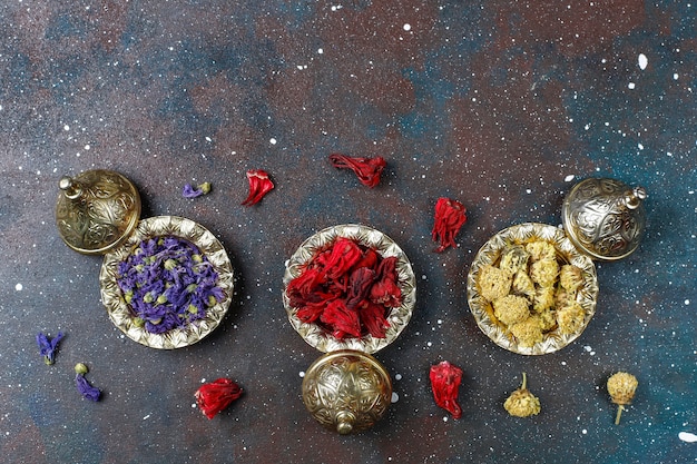 Variedade de chá seco em mini placas vintage douradas. Fundo de tipos de chá