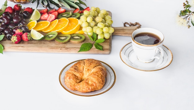 Foto grátis variedade de frutas saudáveis ​​com pão e xícara de chá no fundo branco