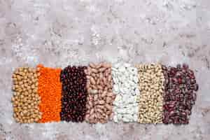 Foto grátis variedade de leguminosas e feijões em tigelas diferentes sobre fundo de pedra claro. vista do topo. comida de proteína vegan saudável.