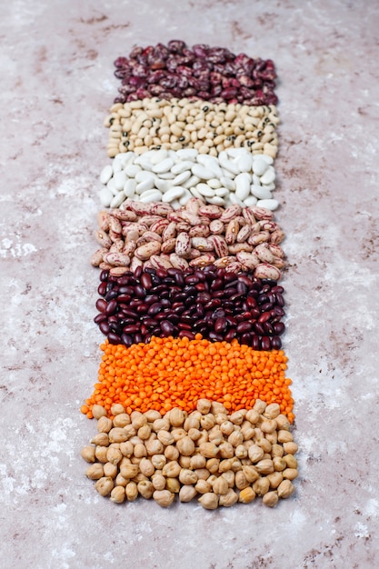 Variedade de leguminosas e feijões em tigelas diferentes sobre fundo de pedra claro. Vista do topo. Comida de proteína vegan saudável.