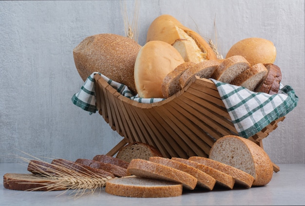 Variedade de pão na cesta na superfície de mármore