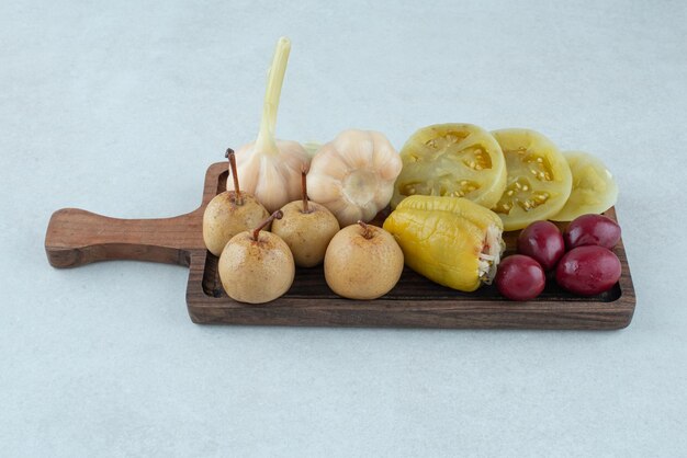 Variedade de saborosos vegetais fermentados na placa de madeira.