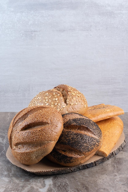 Variedade empilhada de diferentes tipos de pão no fundo de mármore. Foto de alta qualidade