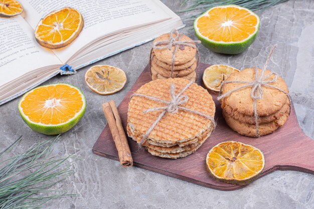 Variedades de biscoitos em uma placa de madeira com canela e laranjas