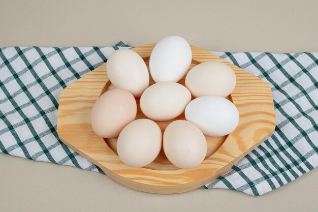 Vários ovos brancos de frango fresco na placa de madeira.