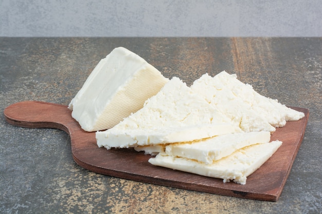 Vários queijo branco na placa de madeira.