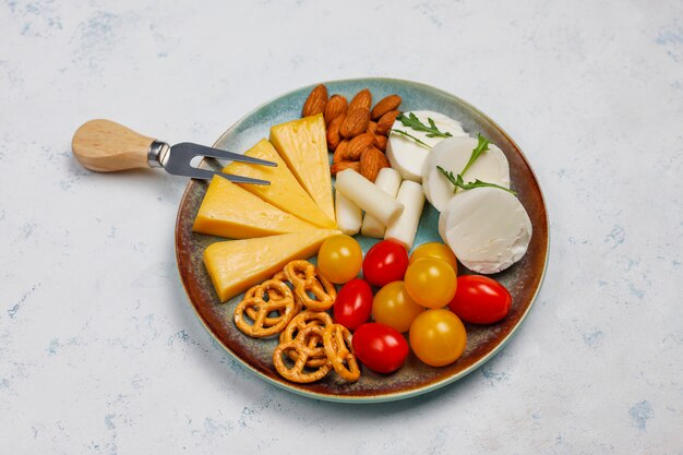 Vários queijo e queijo prato na mesa de luz com frutas e nozes diferentes