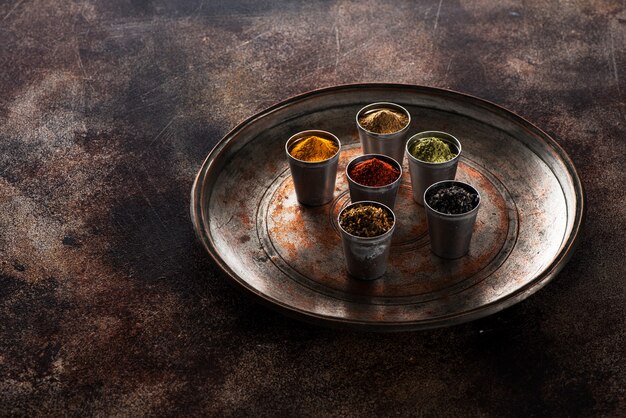 Vários temperos indianos, picantes e temperos em recipientes de metal em um fundo escuro