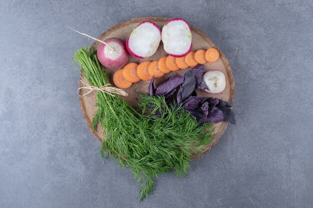 Vários vegetais em uma placa, na superfície de mármore.