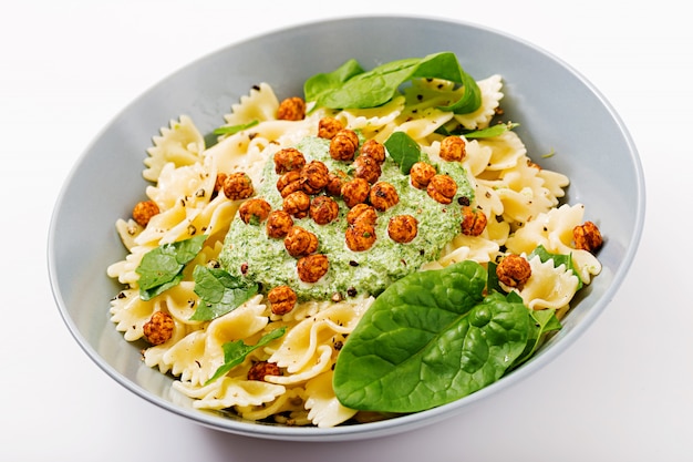 Vegan farfalle macarrão com molho de espinafre com grão de bico frito.