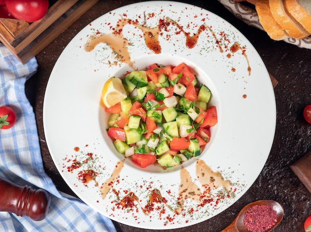 Vegetal, tomate, pepino, salada de roka. salada com sumakh e limão na mesa da cozinha dentro de chapa branca