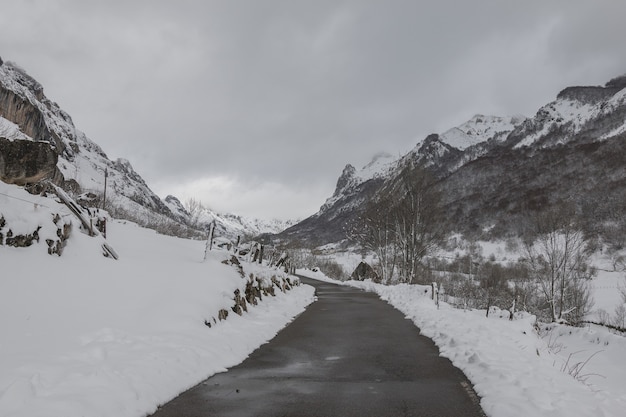 Veja uma estrada estreita com altas montanhas cobertas de neve em ambos os lados