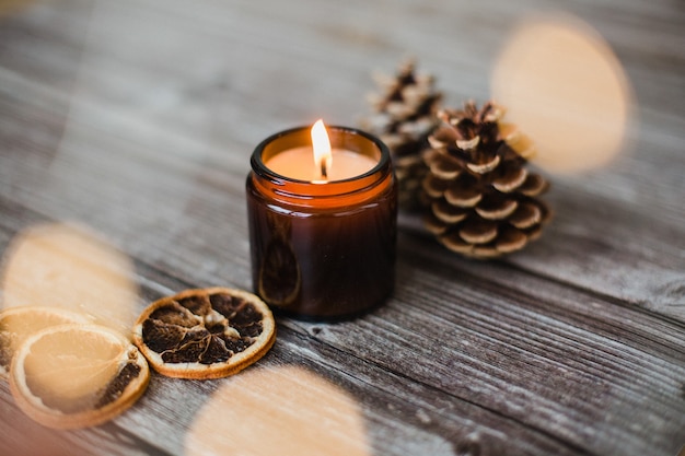 Vela decorativa, rodelas de laranja secas e pinhas