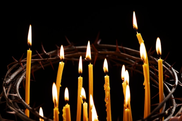 Velas acesas e coroa de espinhos com fundo escuro