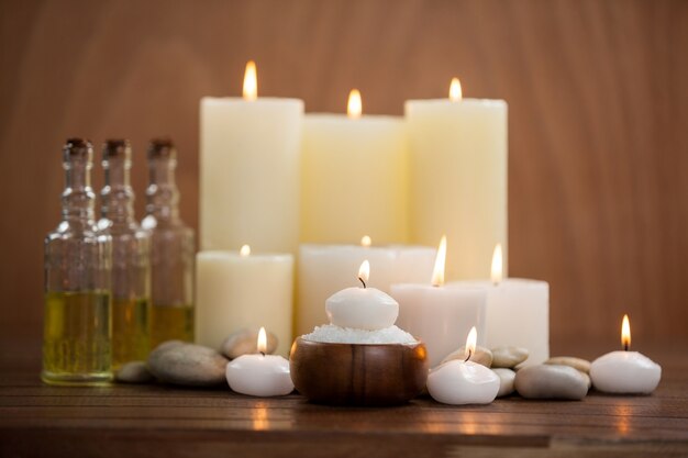 Velas com frascos de óleo de massagem e sal do mar na bacia de madeira