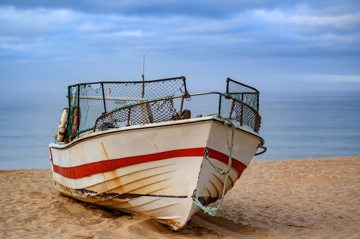 Foto grátis velho barco de pesca enferrujado na areia da praia com vista para o mar atrás