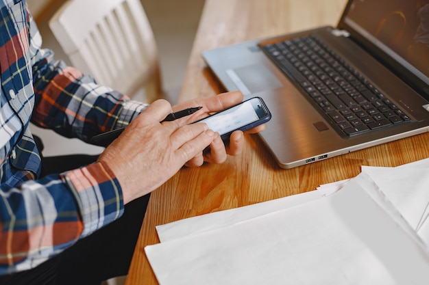 Velho com laptop. Avô sentado em uma decoração de Natal. Homem com telefone celular.