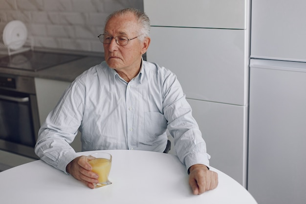 Velho elegante em casa com suco de laranja