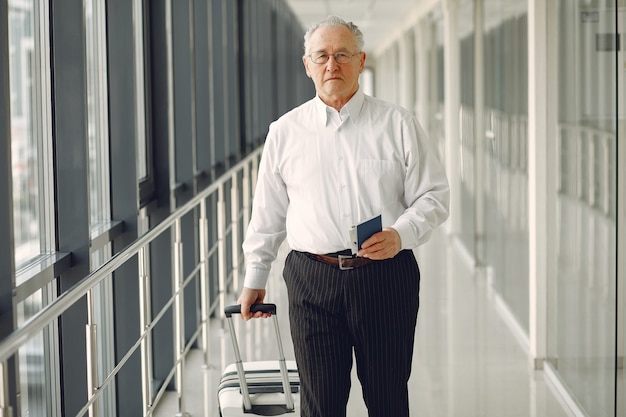 Velho elegante no aeroporto com uma mala