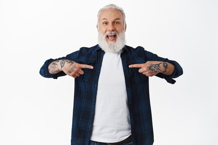 Foto grátis velho feliz com tatuagens e longa barba grisalha apontando para si mesmo com rosto sorridente animado vencendo ou alcançar o objetivo ouvir sobre boas notícias incríveis sobre fundo branco