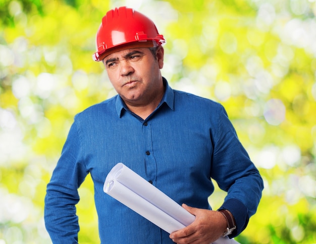 Velho homem com capacete e planos