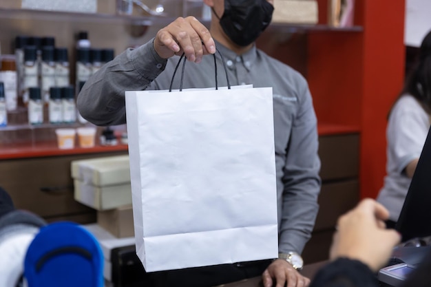 Vendedor dando sacola de compras para o cliente na loja