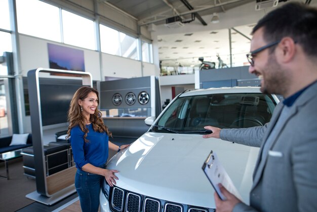 Vendedor de carros apresentando o veículo ao cliente