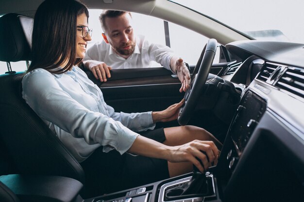 Vendedor e mulher à procura de um carro em um showroom de carros