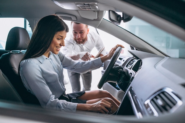 Vendedor e mulher à procura de um carro em um showroom de carros