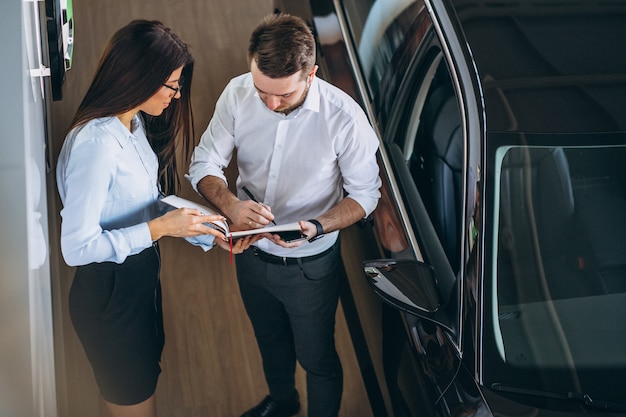 Foto grátis vendedor e mulher à procura de um carro em um showroom de carros