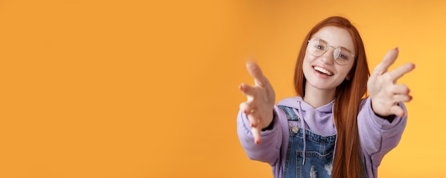 Foto grátis venha aqui vamos segurar atraente tolo amigável feliz sorridente mulher ruiva esticar os braços agarrar a câmera