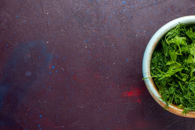 Ver de cima de perto verduras frescas dentro de uma tigela redonda na mesa escura, verduras verdes frescas