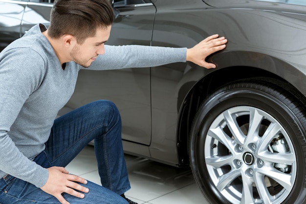 Verificação final Retrato horizontal de um homem verificando pneus em seu carro novo