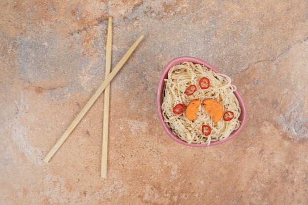 Vermicelli com especiarias e fatias de pimenta em fundo laranja