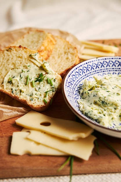 Vertical de fatias de pão de queijo com manteiga de ervas em uma mesa