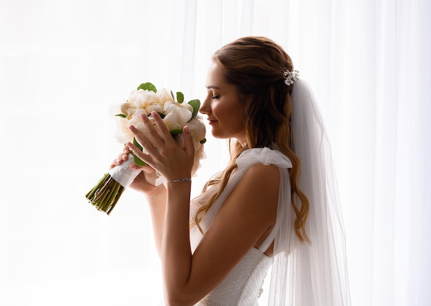 Vestido de noiva segurando e cheirando buquê de casamento