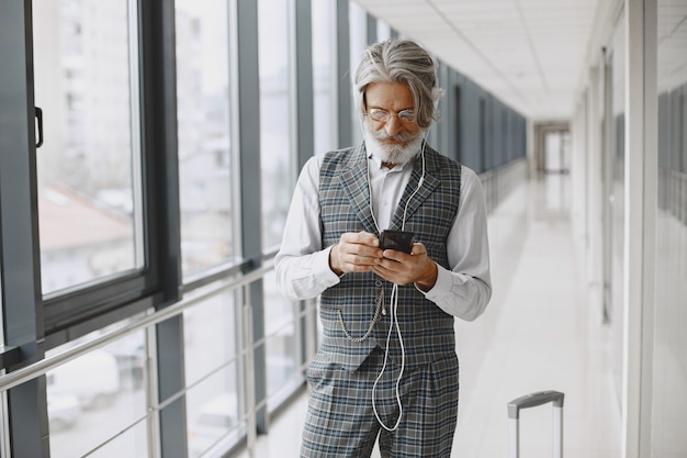 Viagem de negócios. Conceito corporativo e de pessoas. Homem de terno cinza. Sênior com telefone e fone de ouvido.