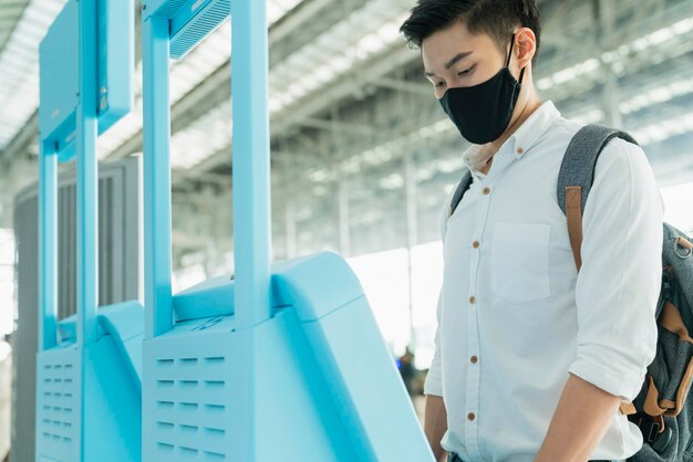 Viagem de negócios masculina asiática, camisa branca, auto-passaporte, check-in com máquina automática, terminal de aeroporto, segurança, conceito de viagem, novo estilo de vida normal