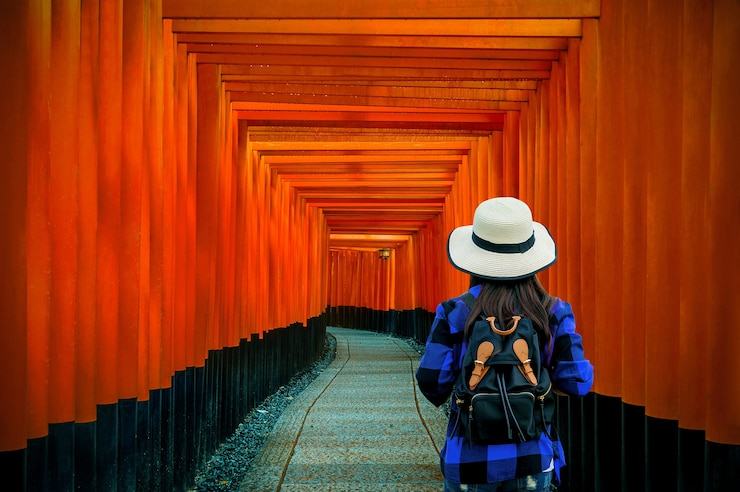 Foto grátis viajante de mulher com mochila no santuário de fushimi inari taisha em kyoto, japão.
