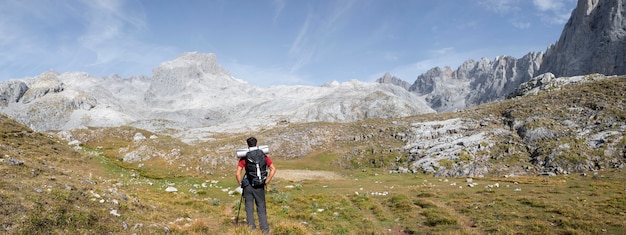 Viajante do sexo masculino caminhando nas montanhas enquanto guarda o essencial em uma mochila