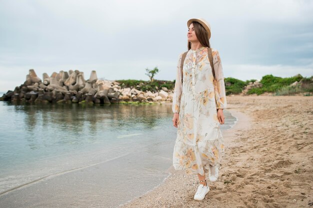 Viajante elegante com chapéu andando na praia