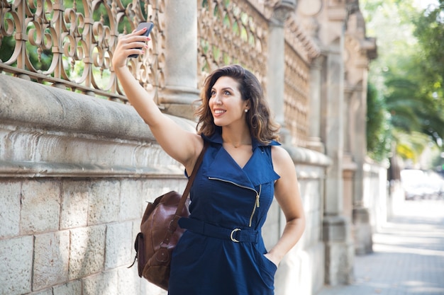 Viajante feminina feliz que leva selfie na rua