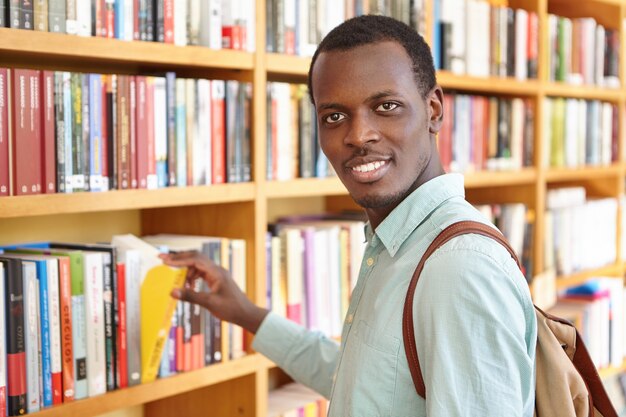 Viajante positivo carregando um livro para escolher a mochila na livraria